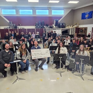 Group of band students, directors, and administrators smile together after receiving the Q3 Grode Grant