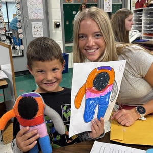 HS and elementary student pose together with the monster drawing and final creation