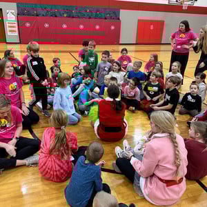A group of HS and elementary students sit together in a gym during part of a holiday event hosted by the Spanish Honor Society
